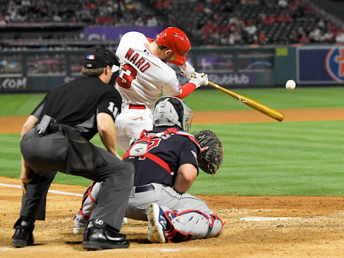 Los Angeles Angels’ Taylor Ward, center, hits a two-run home run as Cleveland Guardians catcher Austin Hedges, right, and home plate umpire Tony Randazzo watch during the seventh inning of a baseball game Monday, April 25, 2022, in Anaheim, Calif.